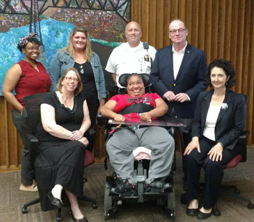 Jessica Rainy (center) was honored by (seated left to right) Human Rights Commission, Jody Miller, the City of Poughkeepsie Mayor Rob Rolison, and Chief of Police, Thomas Pape and Jeanine Byrnes, of Taconic Resources for Independence, for her advocacy that led to the City’s review of their policy and commitment to ensuring events are accessible. (May, 2018)
