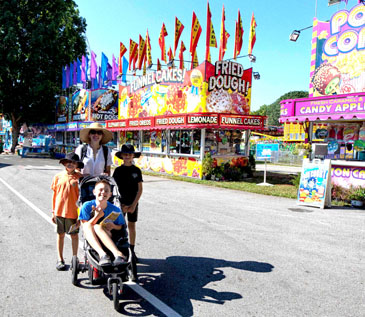 3 youngsters and an accompanying adult smile big for the camera as they enjoyed ThinkDIFFERENTLY Thursday at Dutchess County Fair’s Midway with reduced noises and lights.