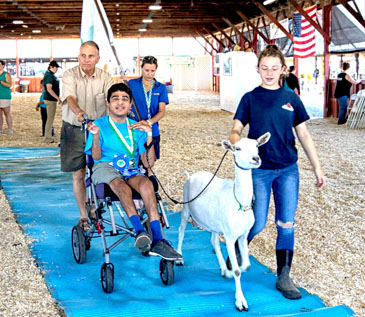 One of the Flourishing Farmers, their mentor, their parent, and their goat (Mallory) open the Showcase on ThinkDIFFERENTLY Thursday at Dutchess County Fairgrounds. Accessibility mats aided in them showcasing Mallory.
