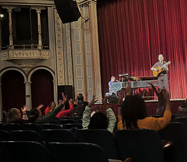 David Gonzalez performed “Cuentos- Tales from the Latino World” at the Bardavon, in partnership with Art Mid-Hudson and Dutchess County Tourism. The audience has their hands raised as part of arm dancing to the story telling music David and Daniel are playing. 3/16/23