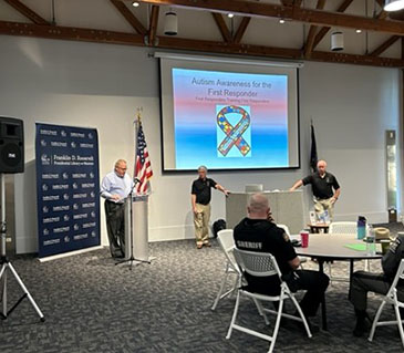Dana Smith, Commissioner of Department of Emergency Response, introduces Retired Captain Bill Cannata, from Westwood Fire Dept in Massachusetts, and Retired Lieutenant Jimmy Donohoe, Pensacola Florida Police Dept. to the attendees of the First Responder Autism Training at the Henry A Wallace Center at The FDR Presidential Library and Museum on Friday April 21, 2023.