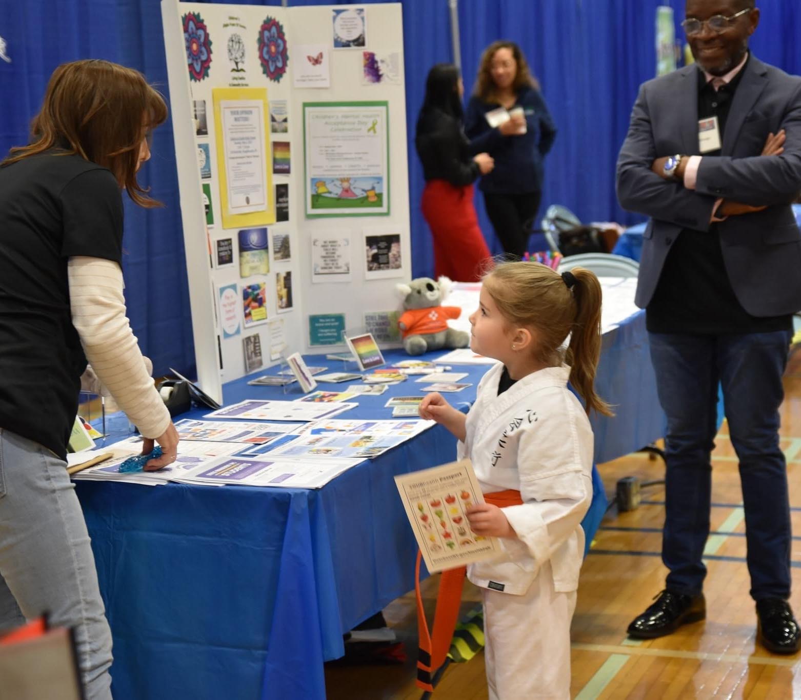 On April 29th, 2023 Dutchess County Department of Behavioral & Community Health hosted their 2nd Annual YOUR Health Fair at Dutchess Community College’s Falcon Hall. Dutchess County’s Children and Youth Services Coordinator, Debbie DiSanza, engages with a young person (a Karate master we gather) at the table about children and youth mental health services in Dutchess County.