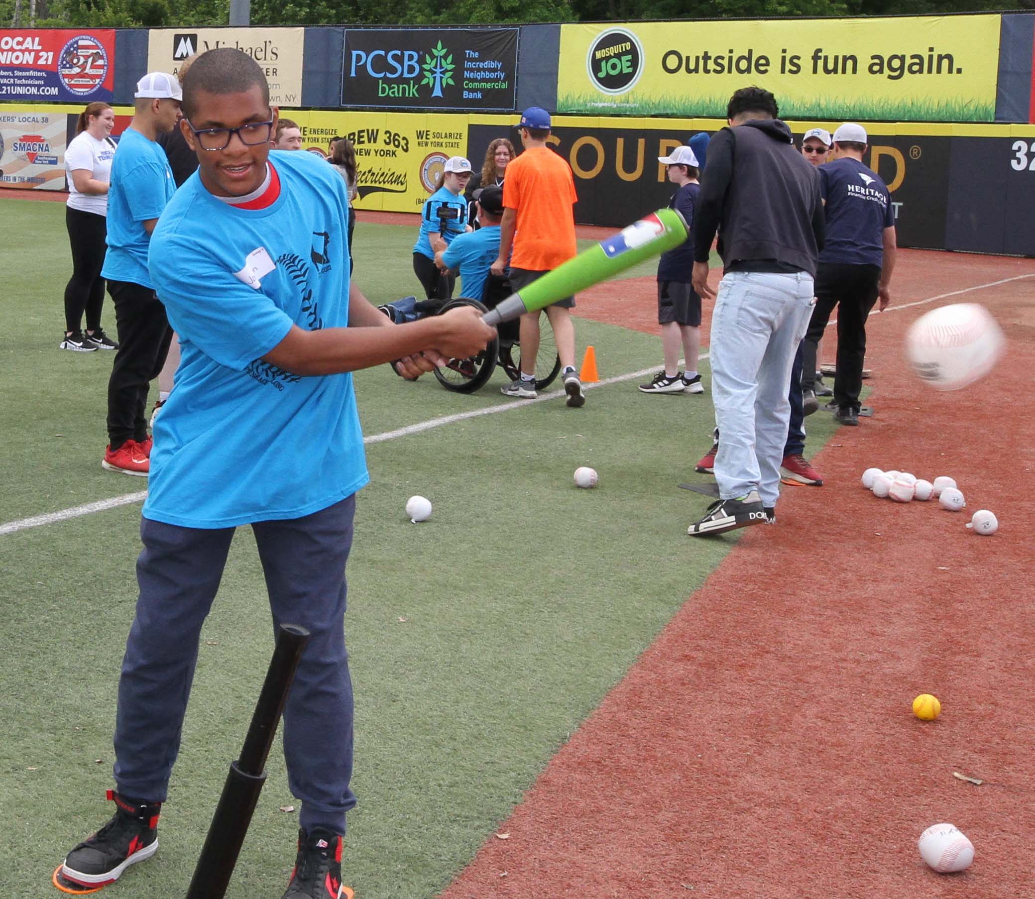 A participant hits a baseball off the tee while smiling. Disability, Dream and Do (also known as D3 Day) at Heritage Financial Field, June 17, 2023.