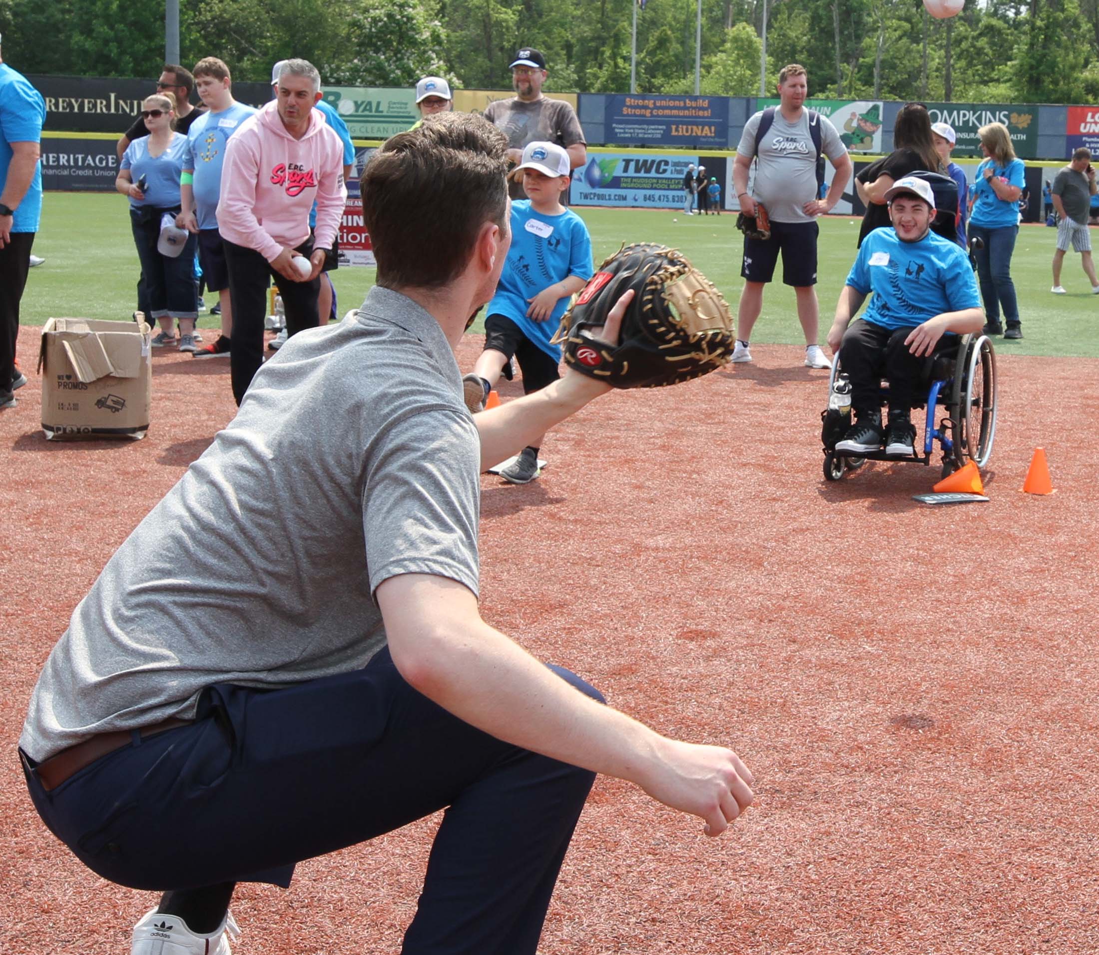 Participants throw baseballs to Hudson Valley Renegades Players. In this picture a youngster is partially hidden by a HV Renegades player, but he is in the motion of throwing a baseball, while another young man, who is seated in wheelchair, has already thrown the ball to the HV Renegades player as the ball is in the air between the two of them. Disability, Dream and Do (also known as D3 Day) at Heritage Financial Field, June 17, 2023